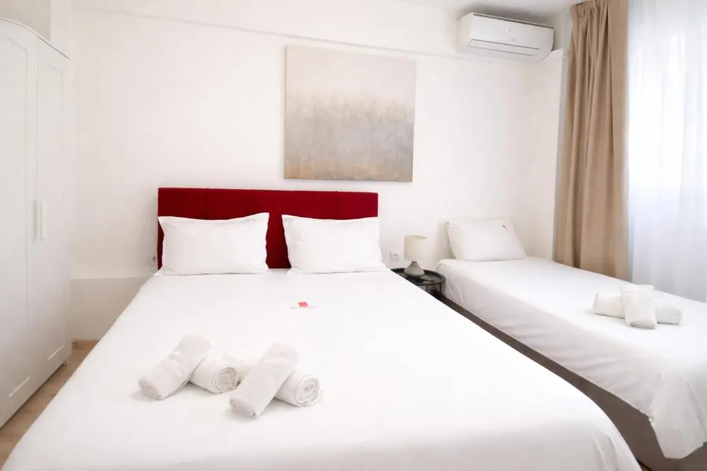 close up photo of the Triple room of City Plaza hotel featuring one large double bed and a single bed next to it with neatly folded towels on top of them